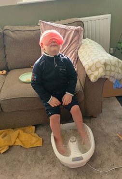 Little boy with eye mask on and feet in foot spa