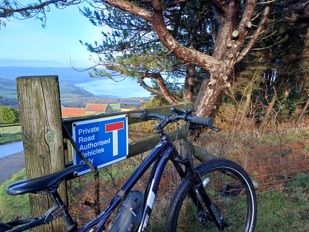 Bike leaning against a fence with a view of the coast in the background